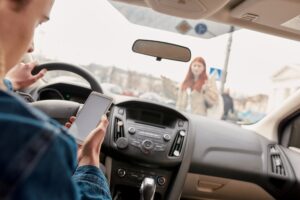 Distracted young male driver looking at the screen of his mobile phone while running over a pedestrian.