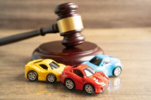  Judge's gavel and car accident scene symbolizing insurance coverage, claim, lawsuit, and court case.