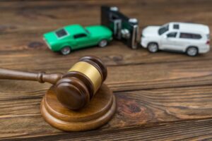 A judge's gavel with a car accident in the background, symbolizing legal matters related to traffic accidents, insurance claims, and fault determination.