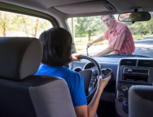 Woman driving and texting on cell phone, about to hit a man on a bicycle.