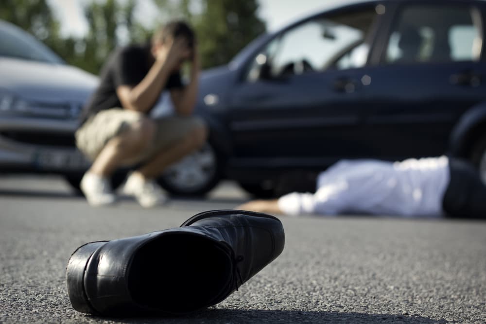 An injured pedestrian lying on the road after being hit by a car.