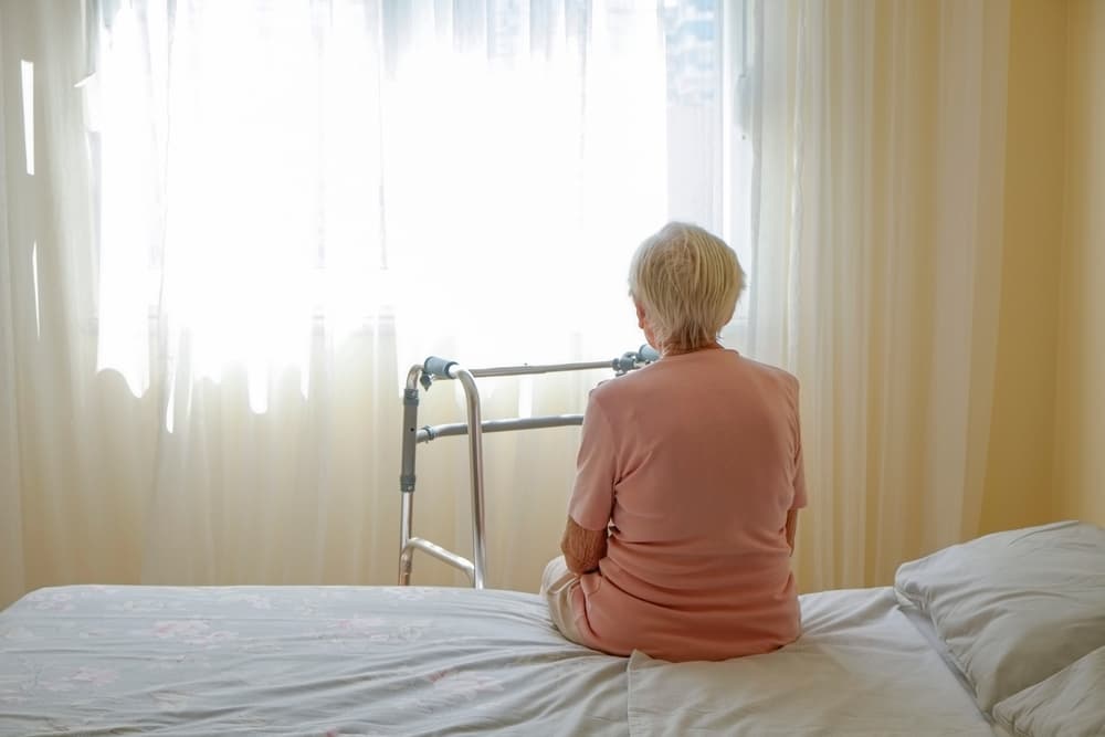 Elderly woman in a nursing home holding a walking frame with her wrinkled hand. Close-up of her grasping the walker’s handles, with an interior background.