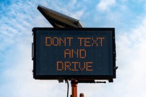 Digital road sign in front of blue sky with text Dont text and drive to convey a concept of distracted driving prevention and awareness