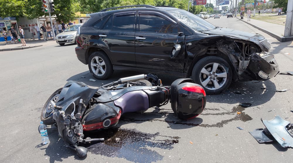 Car collision: Toyota Lexus and Honda motorcycle accident on city street at a crossroads