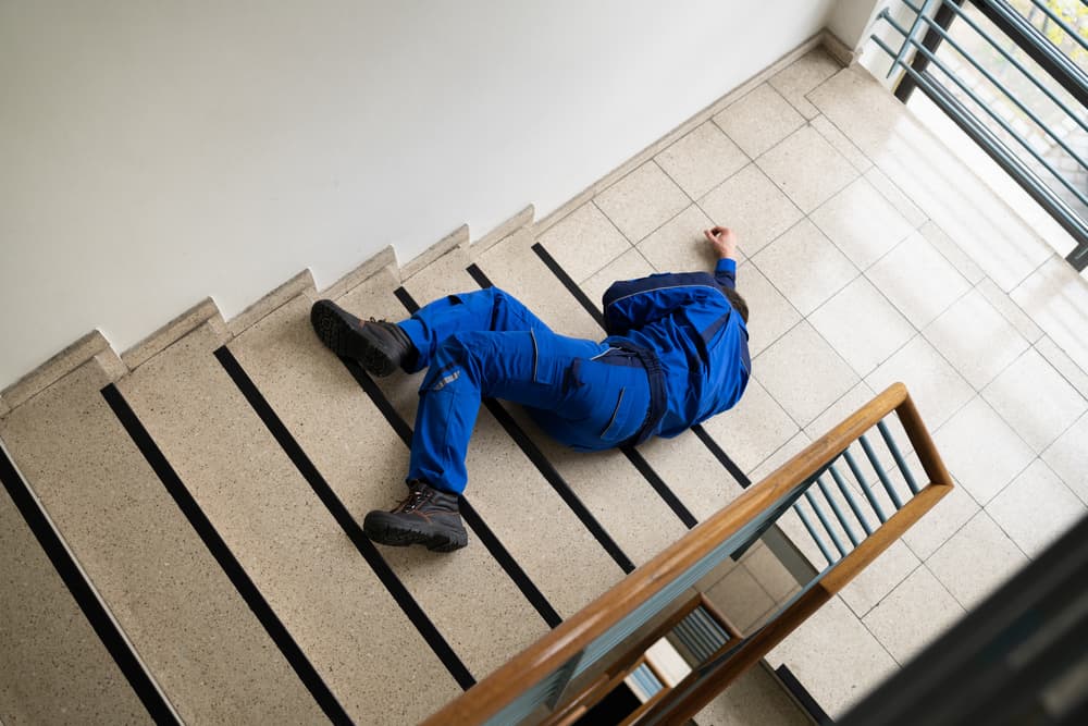 Worker lying on a staircase after a slip and fall accident.