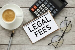 Top view of a notepad with 'Legal Fees' text, a calculator, and a cup of coffee on a work table