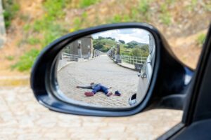 A pedestrian lies dead on the road, seen through a rearview mirror, illustrating a fatal hit-and-run accident.